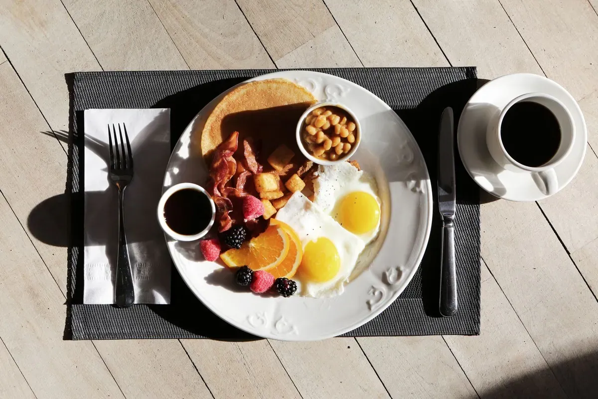 Desayuno con huevos, bacon, tostada, naranja y café